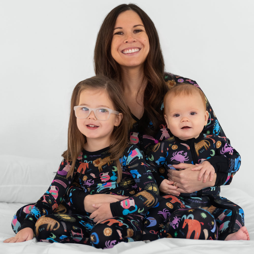 Mother and her two children wearing matching Star Signs pjs. Dressed in women's pj top and bottoms, and children's zippy and two piece styles.