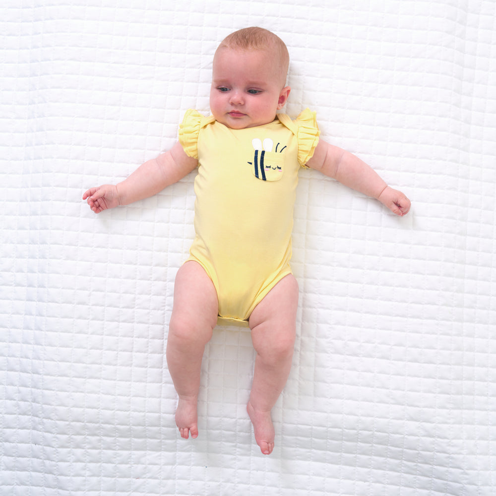 Child laying on a bed wearing a Lemon Twist Graphic Flutter Bodysuit