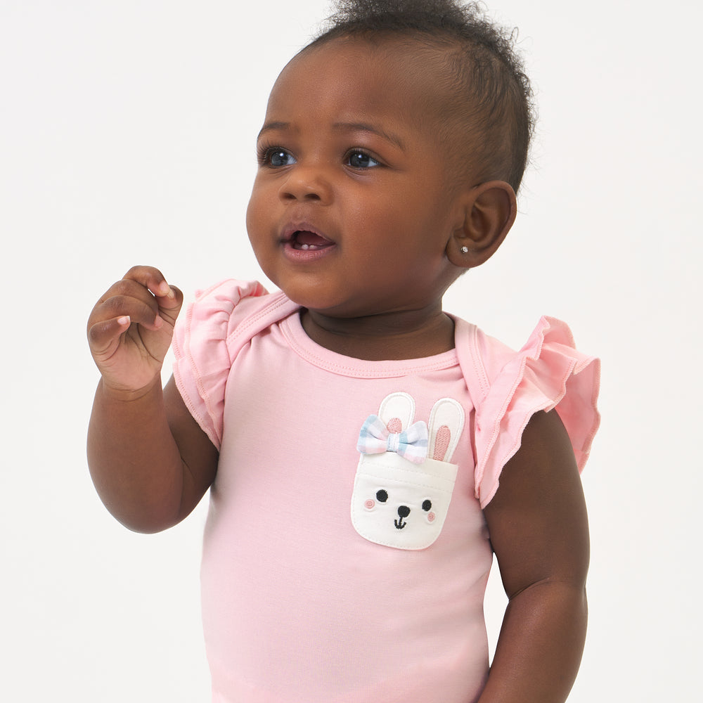 Click to see full screen - Close up image of a child wearing a Pink Blossom flutter pocket bodysuit