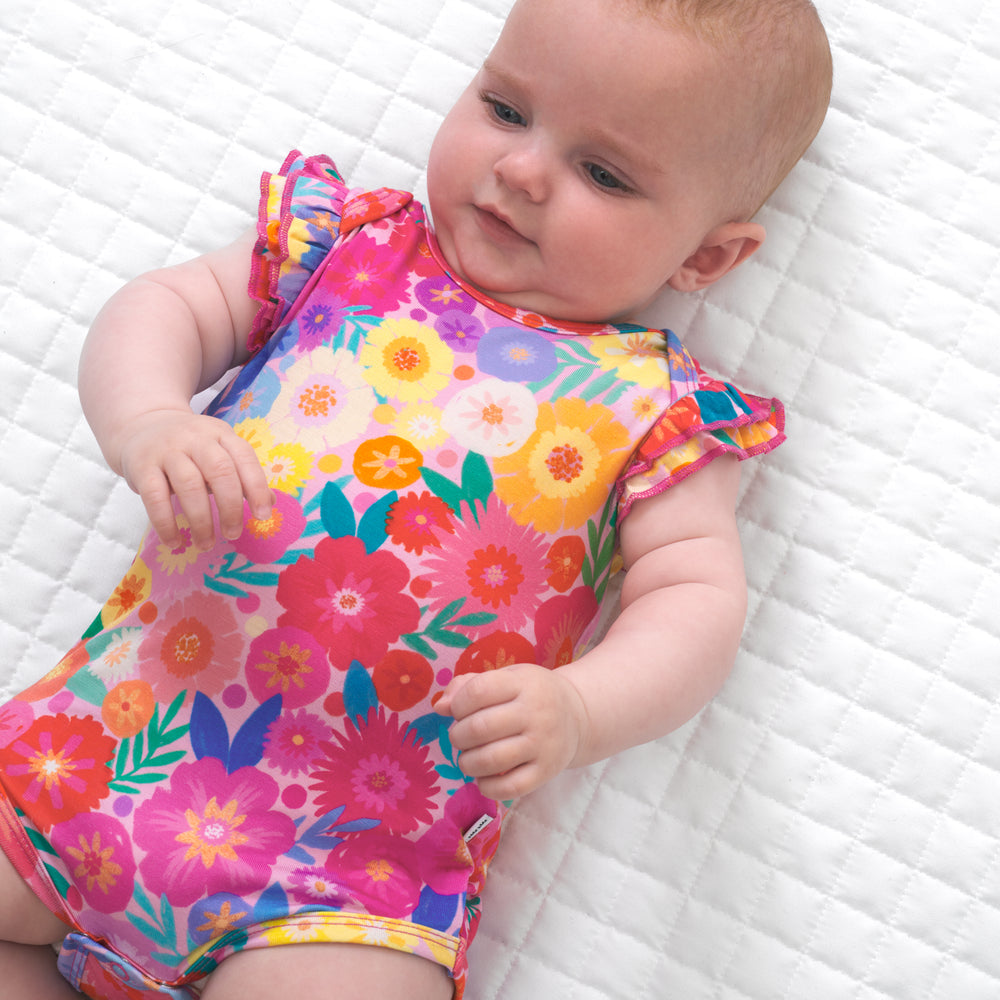 Close up image of a child laying on a blanket wearing a Rainbow Blooms flutter bodysuit
