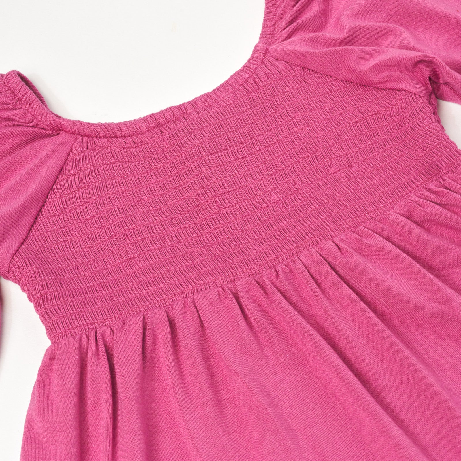 Close up flat lay image of a Berry Rose Peasant Smocked Top