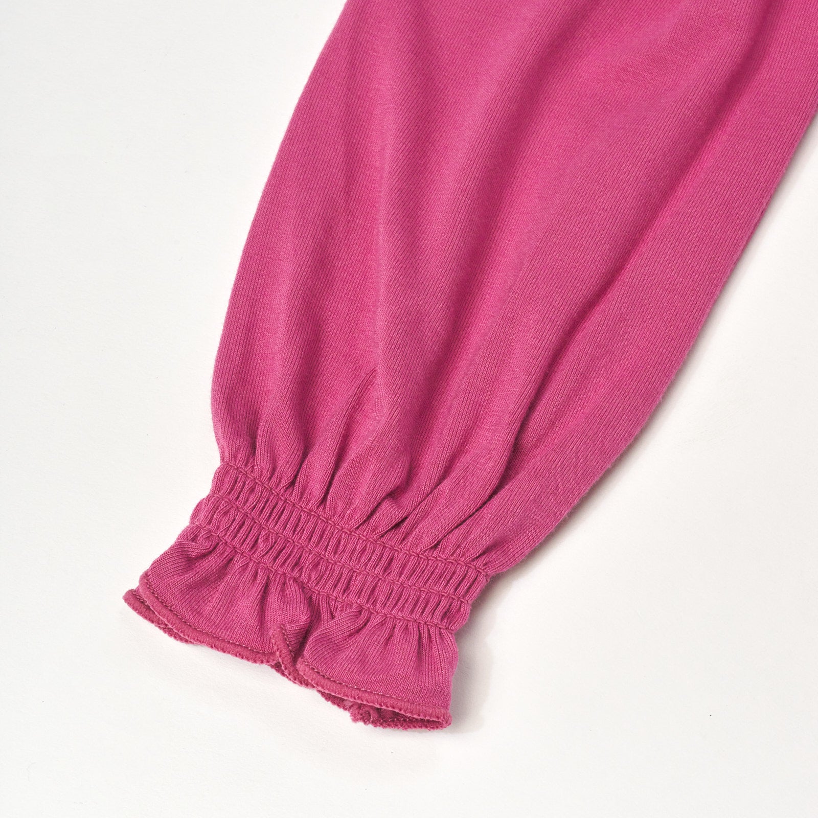 Close up flat lay image of Berry Rose Peasant Smocked Top detailing the sleeve cuff.