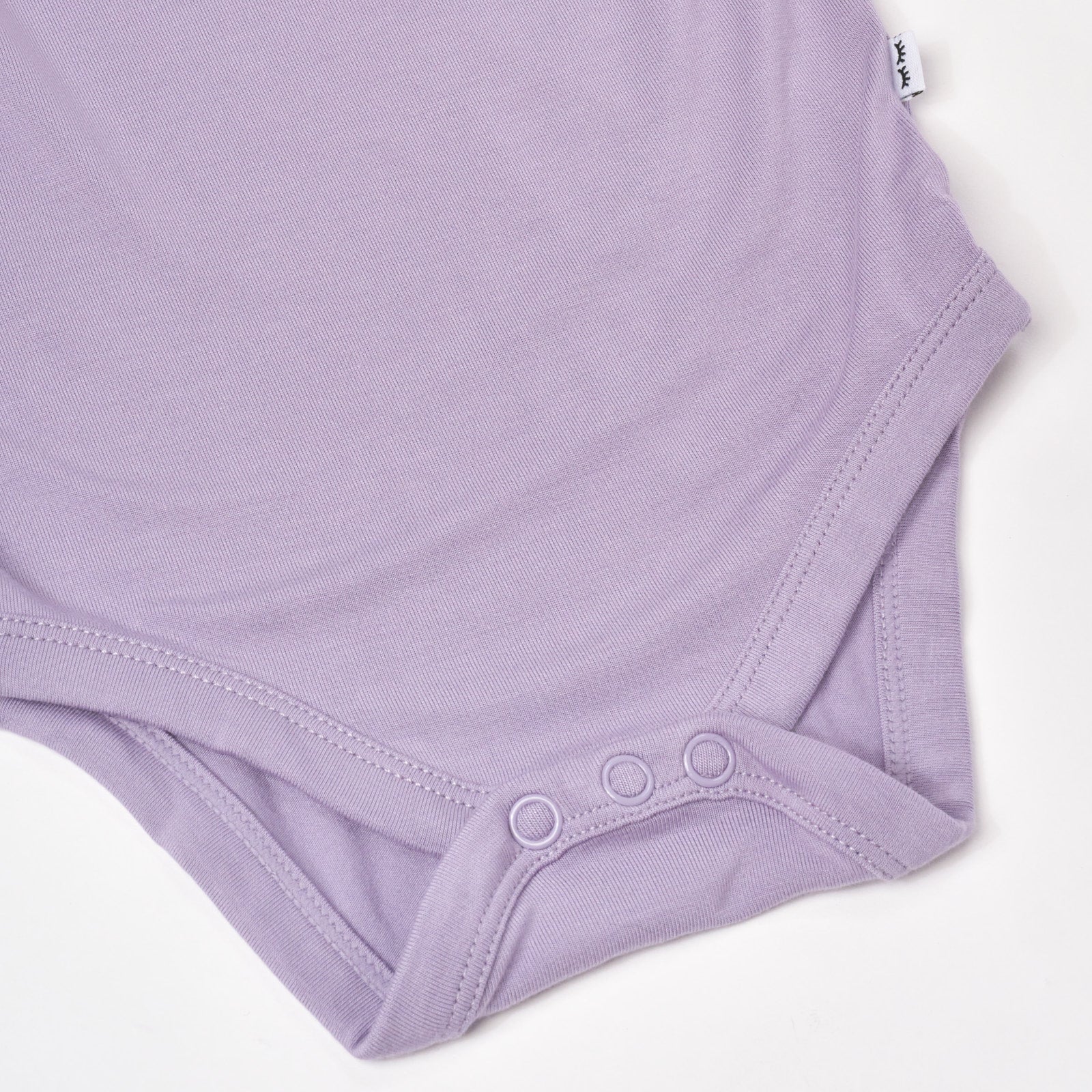 Close up flat lay image of Dusty Lavender Flutter Bodysuit detailing the button snaps at the bottom