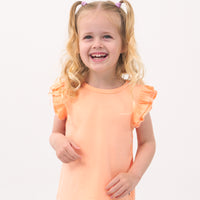 Close up image of a child wearing a Peach Nectar flutter tee