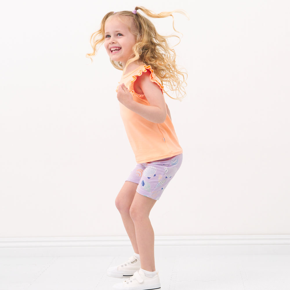 Side view image of a child wearing a Peach Nectar flutter tee and coordinating bike shorts