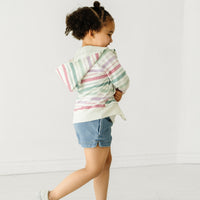 Side view image of a child wearing a Winter Stripes zip hoodie and coordinating Play outfit
