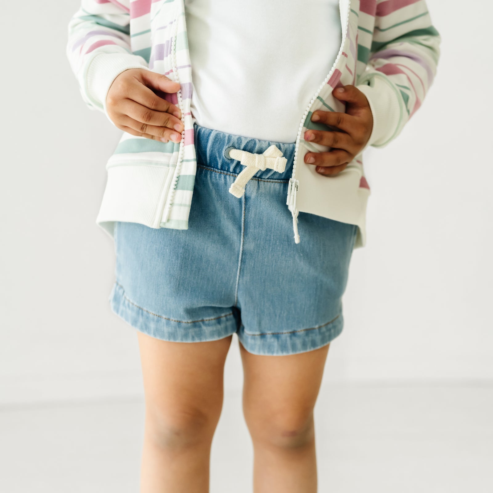 Close up image of a child wearing Light Blue denim shorts and a coordinating top