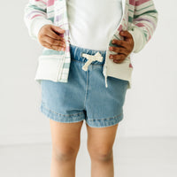 Close up image of a child wearing Light Blue denim shorts and a coordinating top