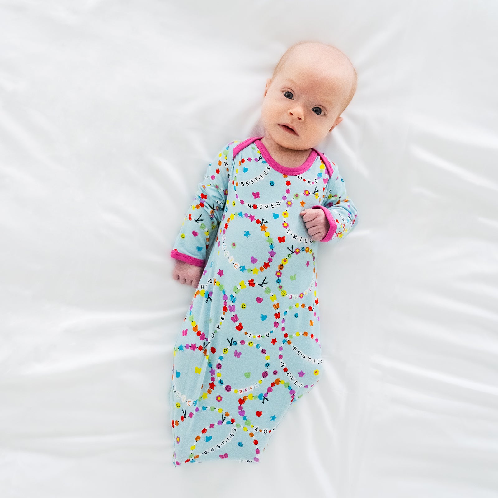 Aerial view of child laying on a bed wearing a Friends Forever Bamboo Infant Gown