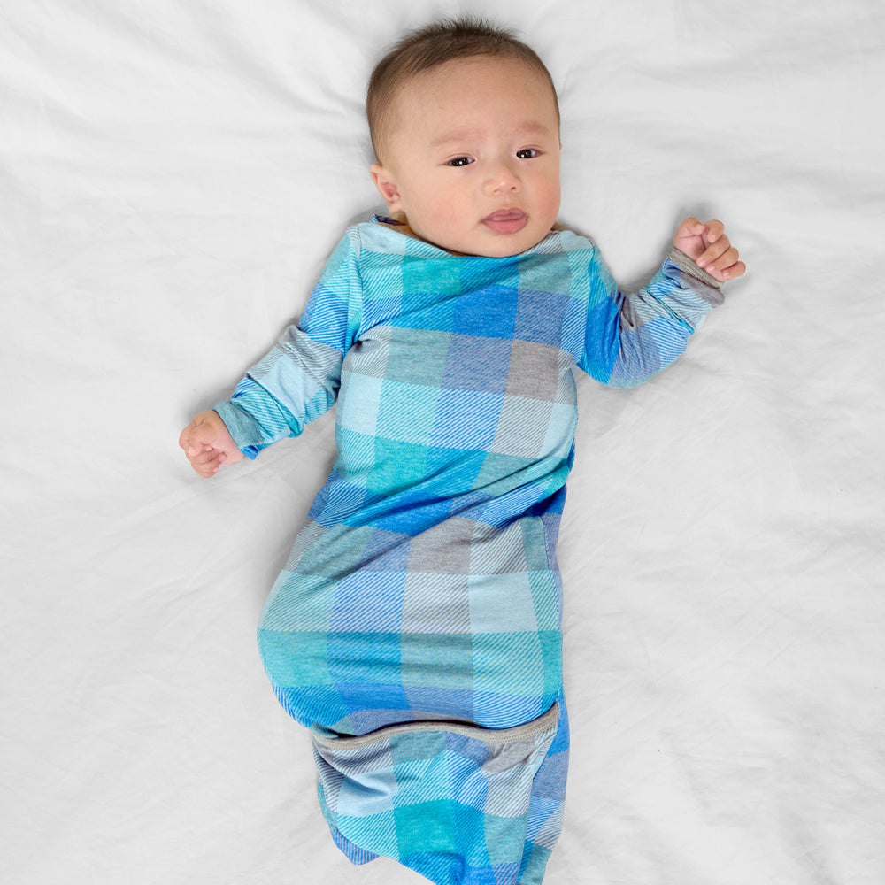 Image of a child laying on a bed wearing an Arctic Plaid infant gown
