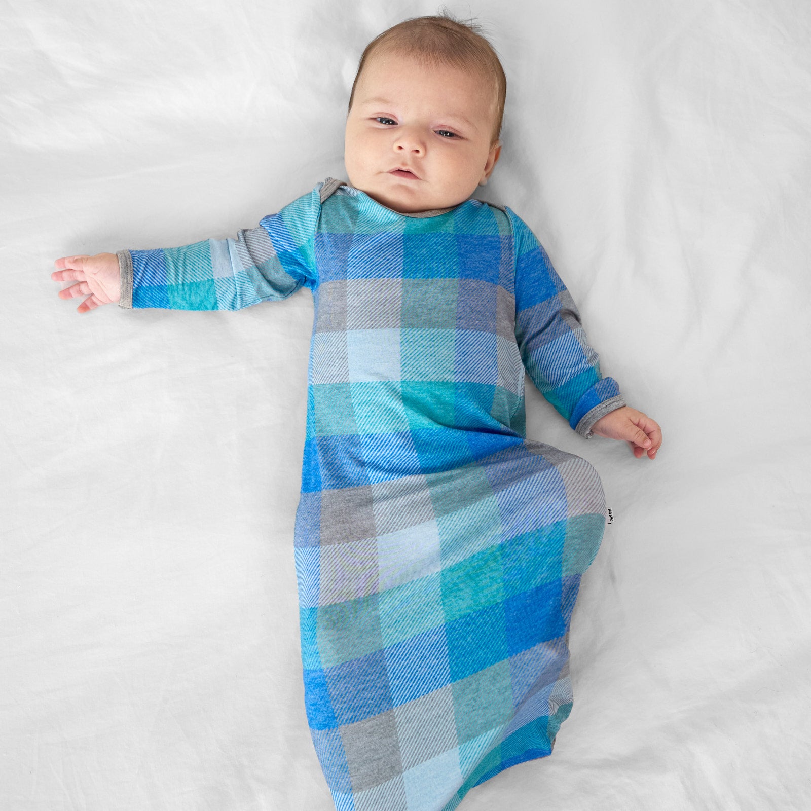 alternate image of a child laying on a bed wearing an Arctic Plaid infant gown
