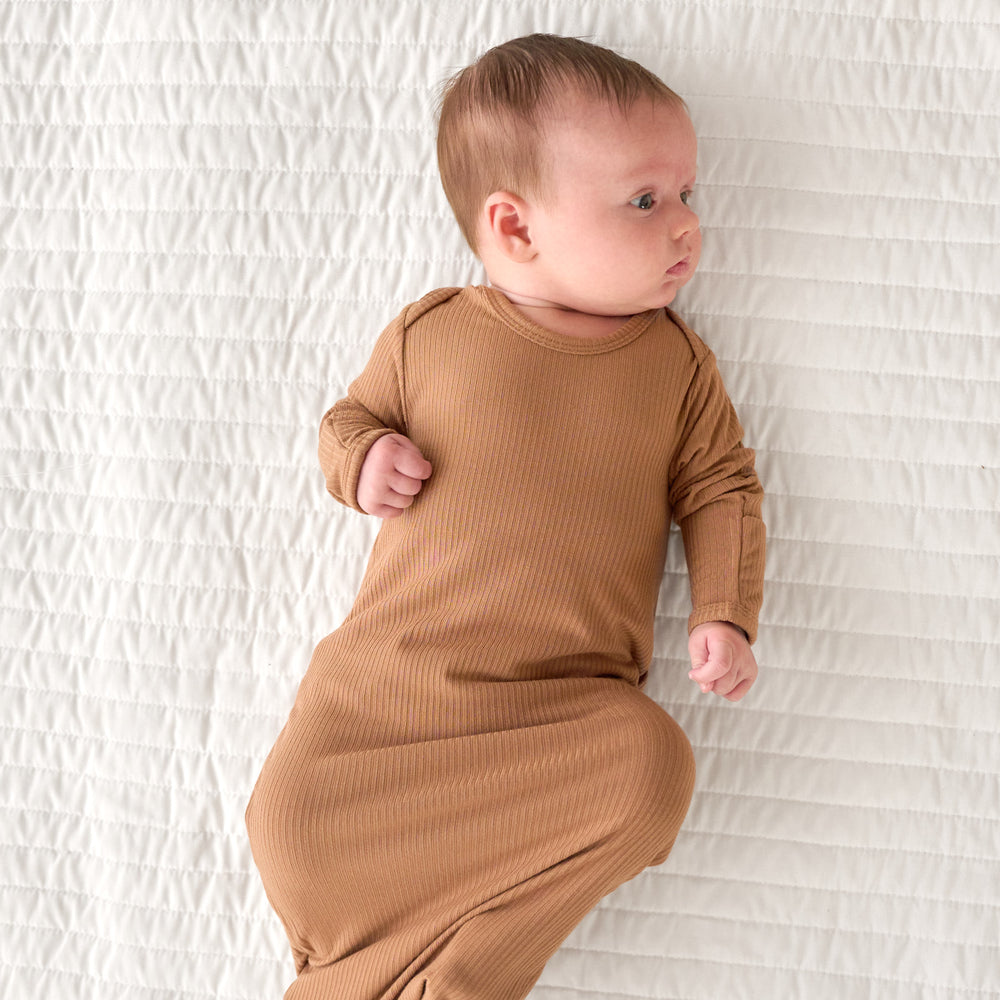 Top view image of baby laying down while in the Caramel Ribbed Infant Gown