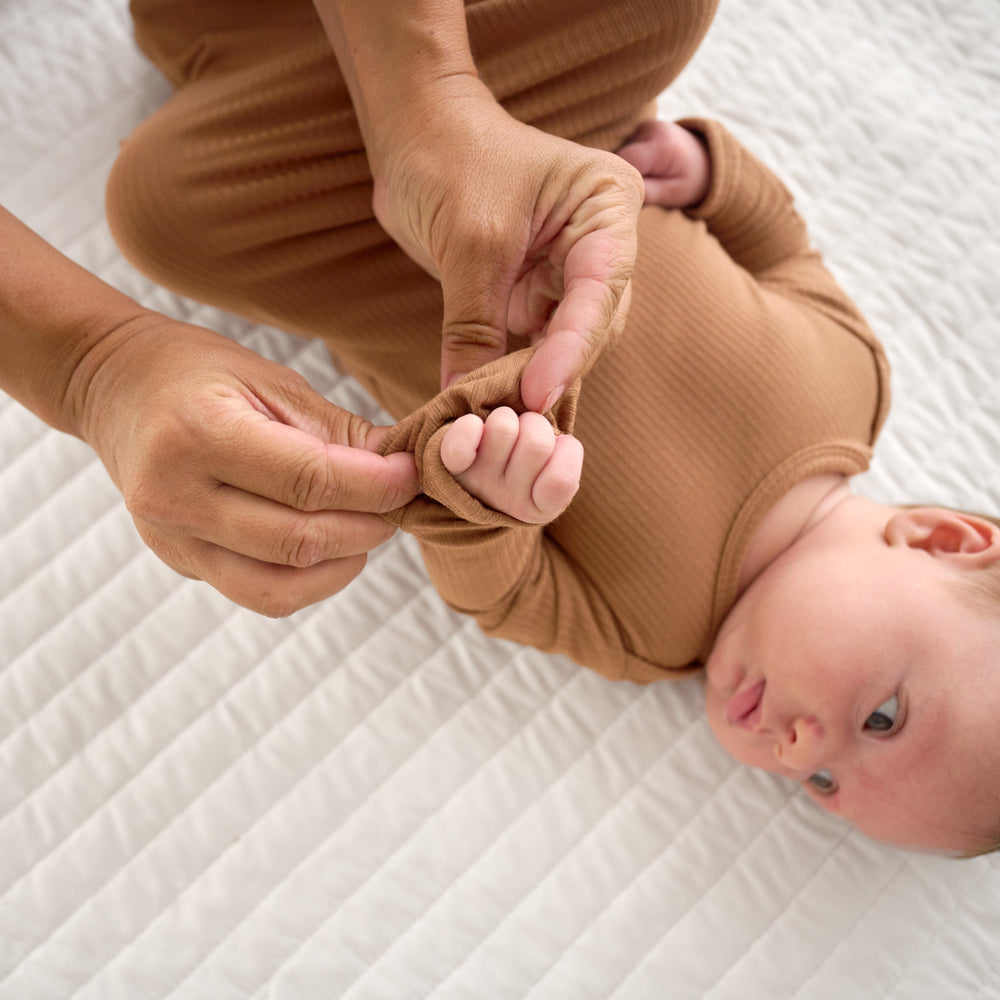 Close up image of the fold over hand detail on the Caramel Ribbed Infant Gown