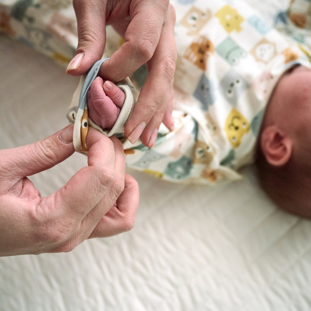 Close up image of a parent folding over the mittens of a Check Mates Infant Gown on an infant