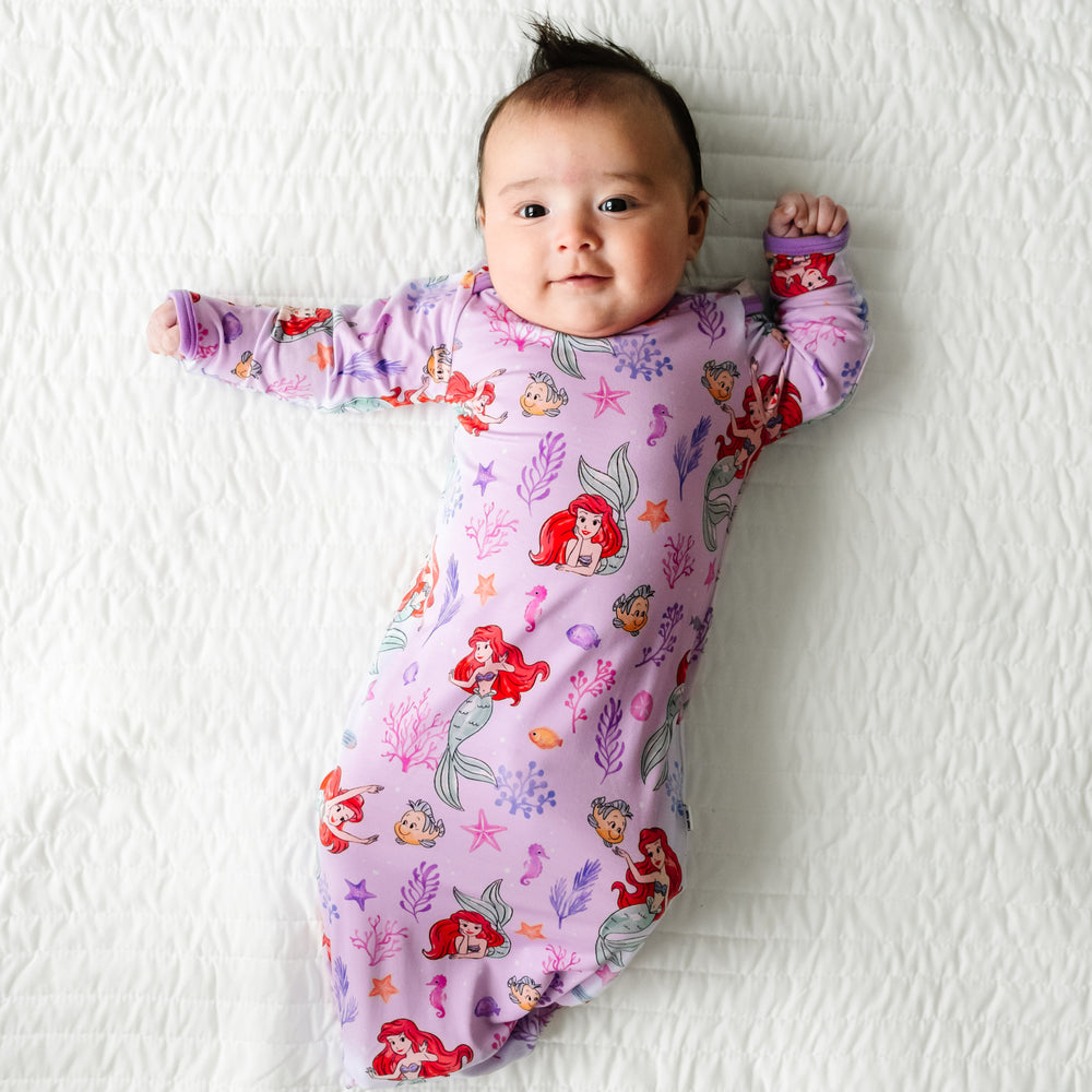 Child laying on a bed wearing a Disney Part of Her World infant gown