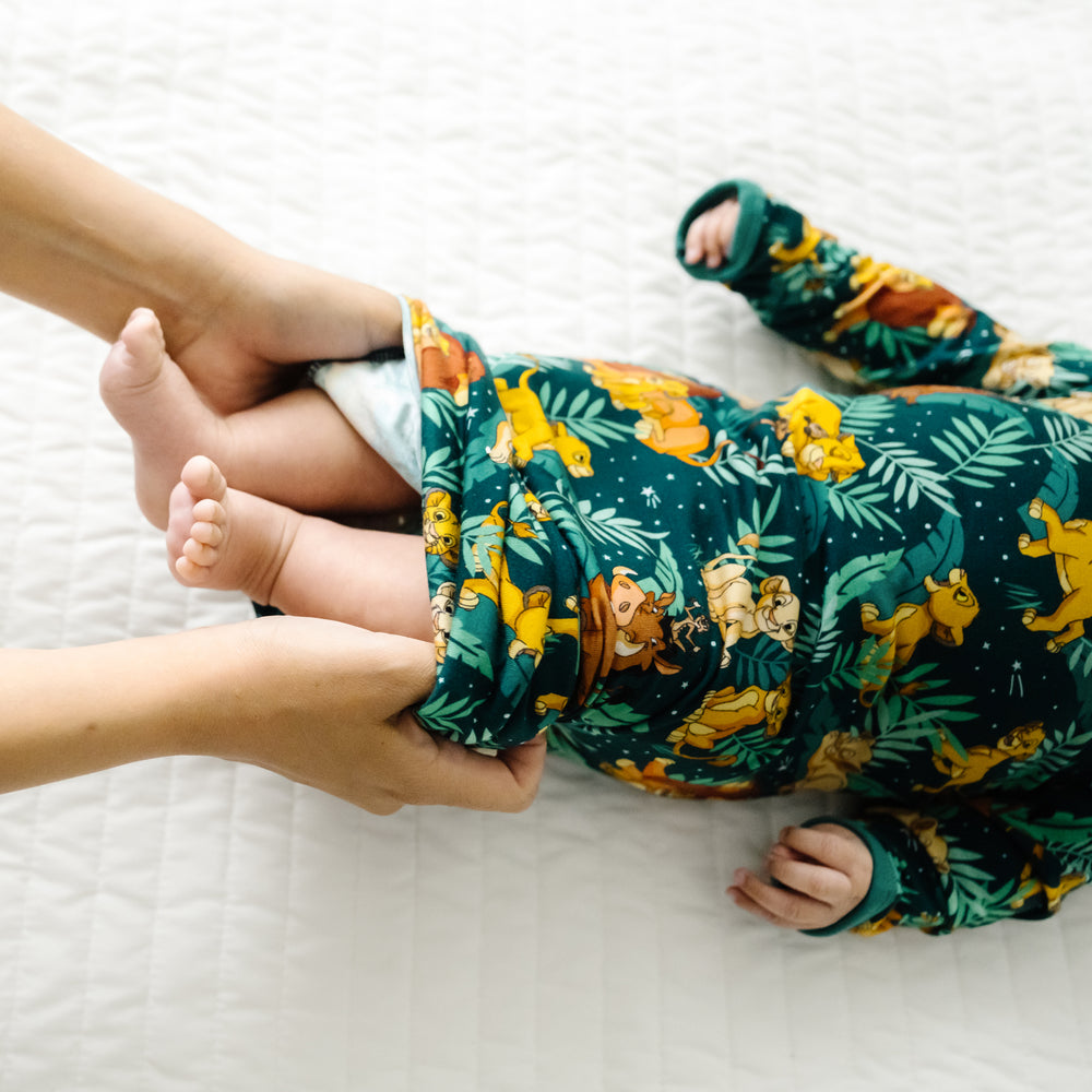 Close up image of a mom folding over the hem of a child wearing a Disney Simba's Sky infant gown