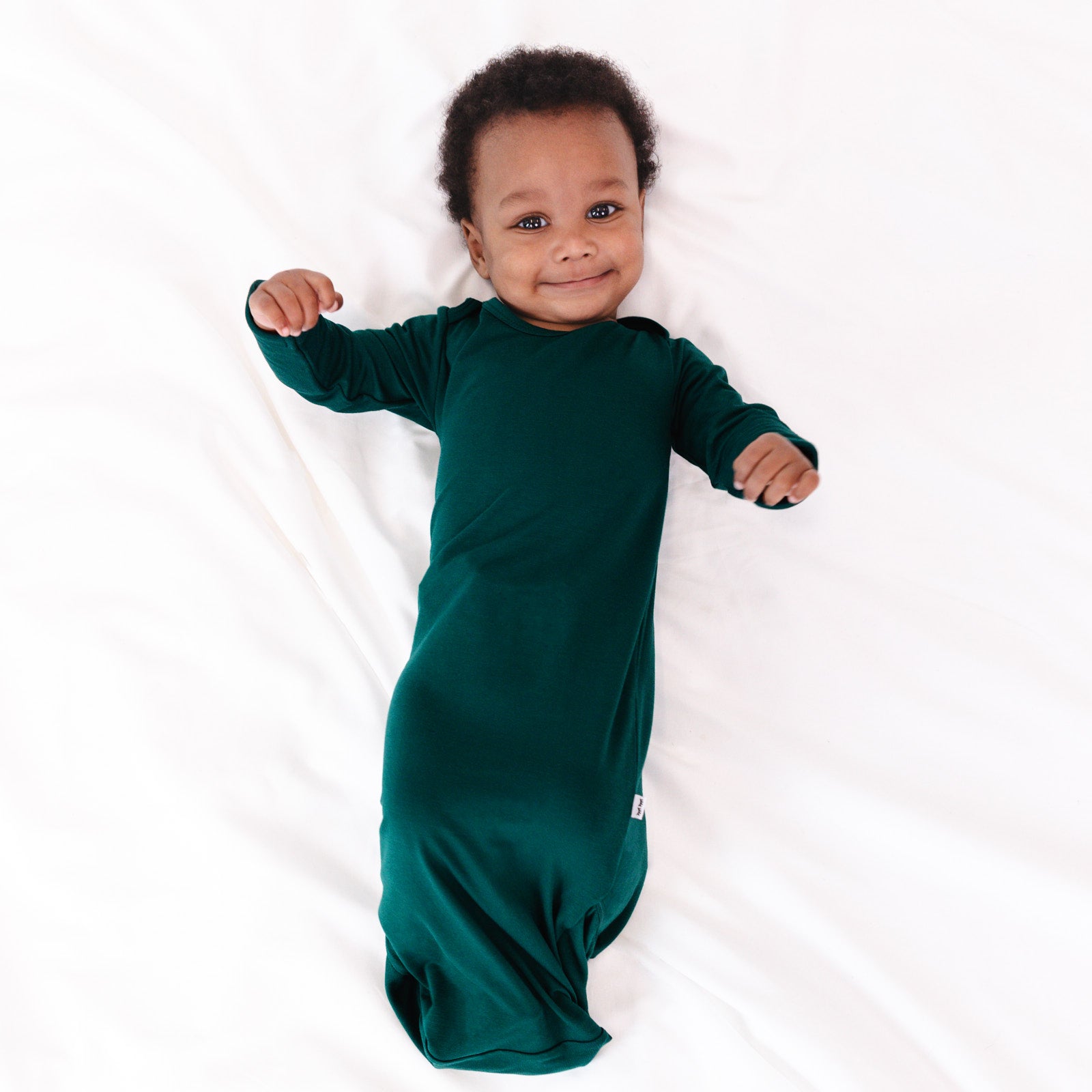 Top view image of baby laying down while wearing the Emerald Infant Gown