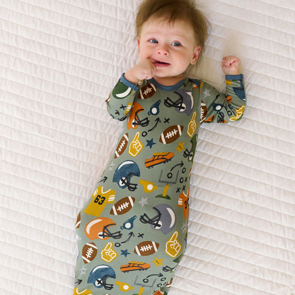 Top view image of baby laying down while in the Touchdown Time Infant Gown