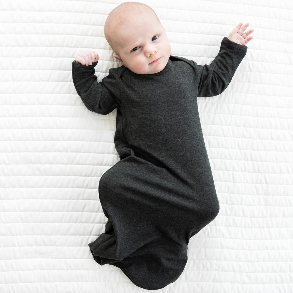 Child laying on a bed in a Cozy Heather Black infant gown