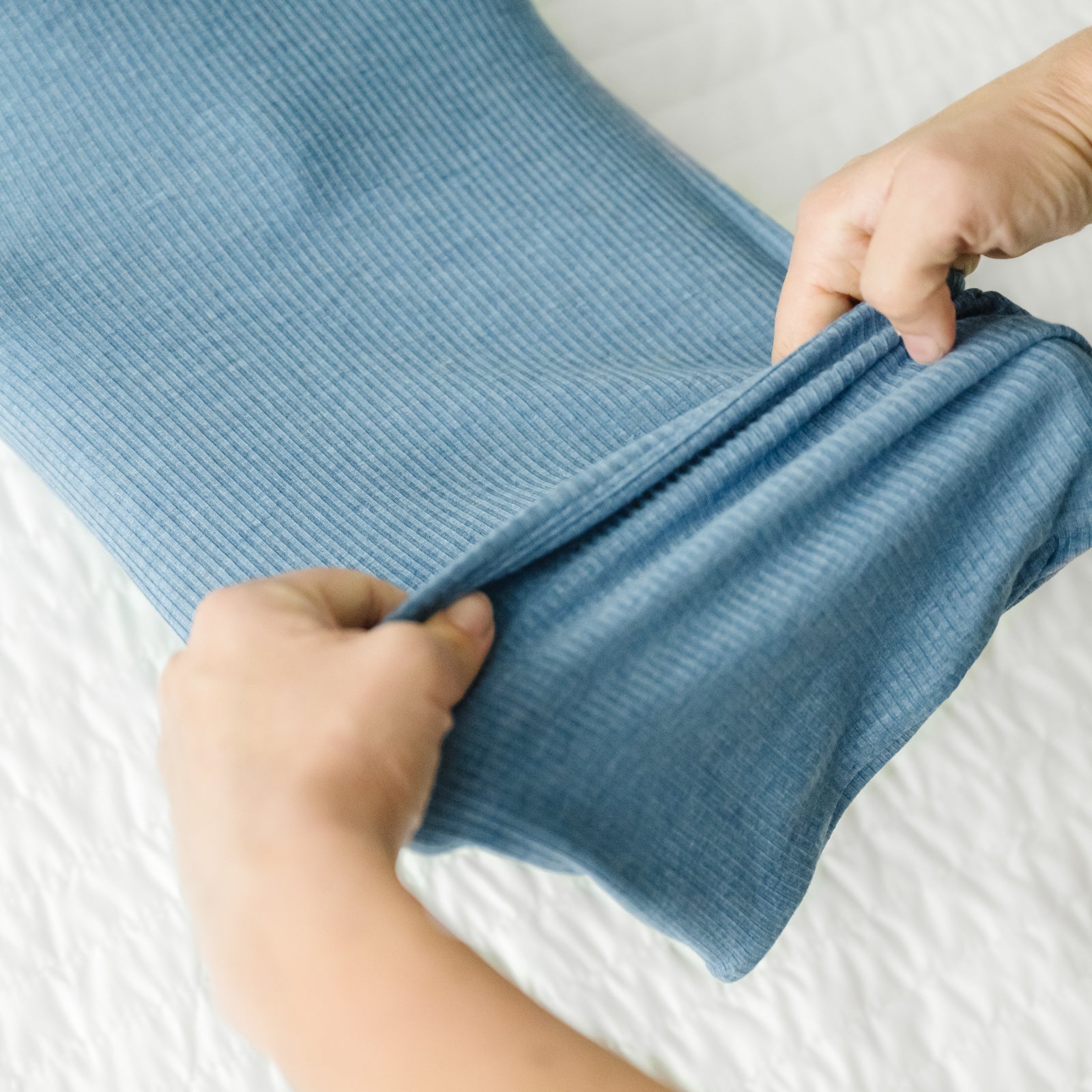 Alternate image of a child laying on a bed wearing a Heather Blue Ribbed Infant Gown demonstrating the fold over bottom