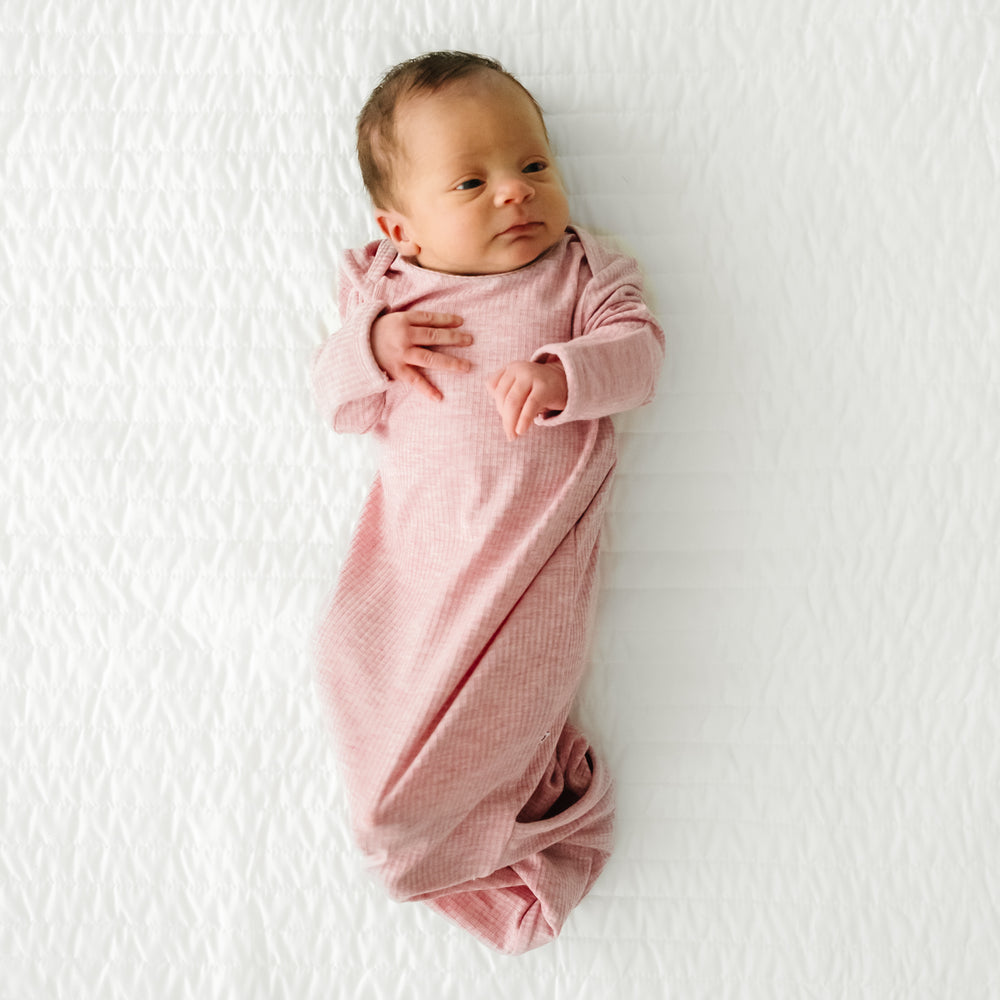Child laying on a bed wearing a Heather Mauve Ribbed Infant Gown