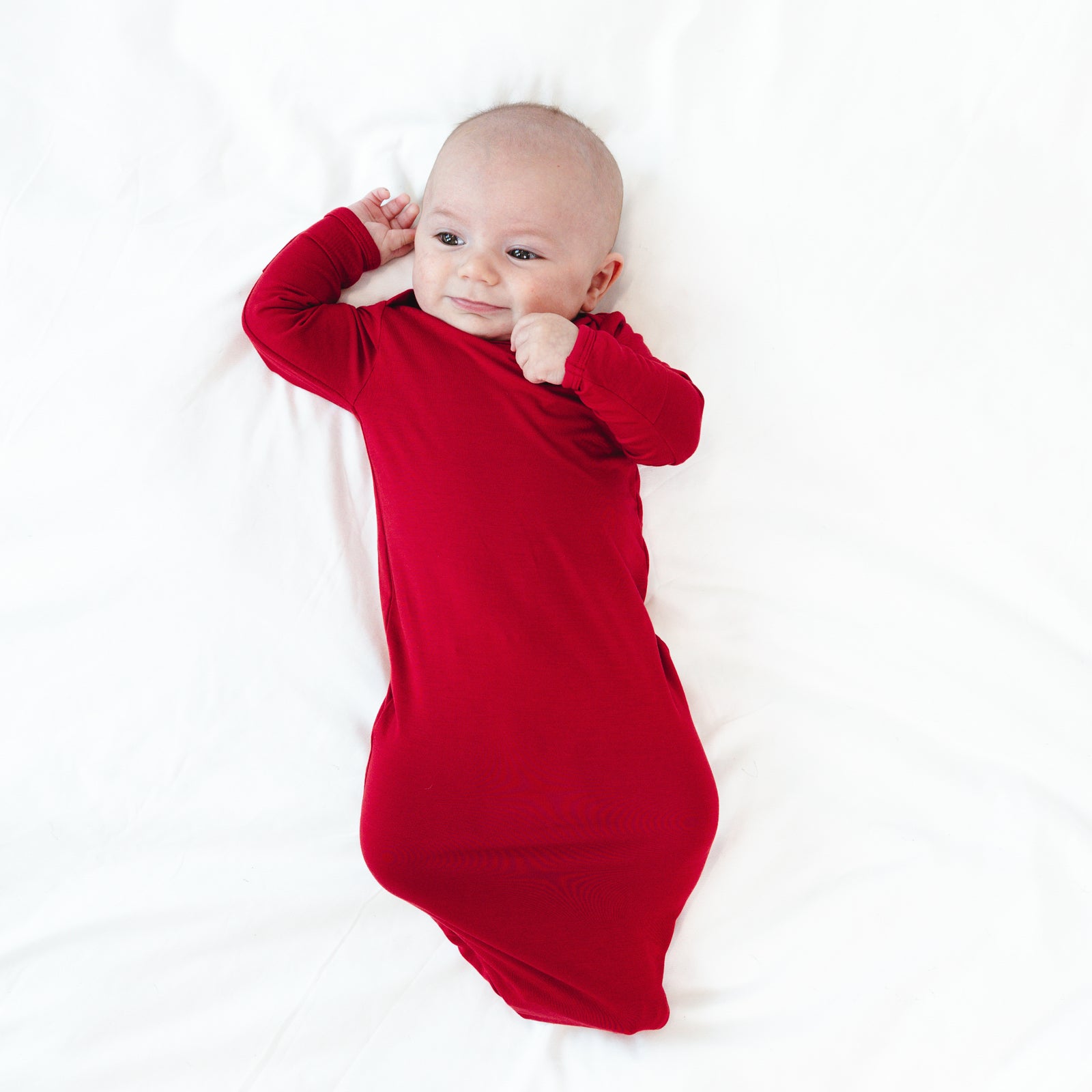 Top view image of baby laying down while wearing the Holiday Red Infant Gown