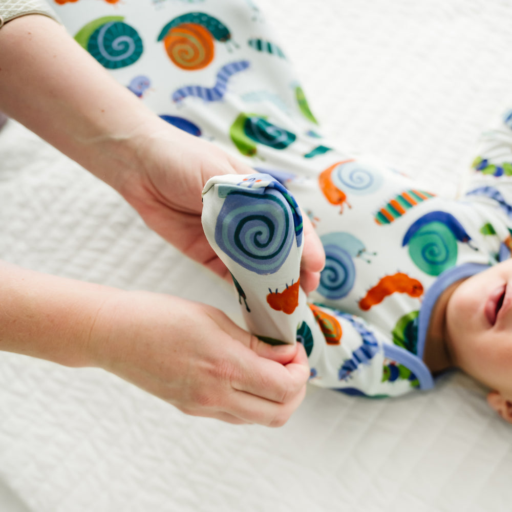 Close up image of an infant wearing an Inchin' Along infant gown, detailing the fold over mitten