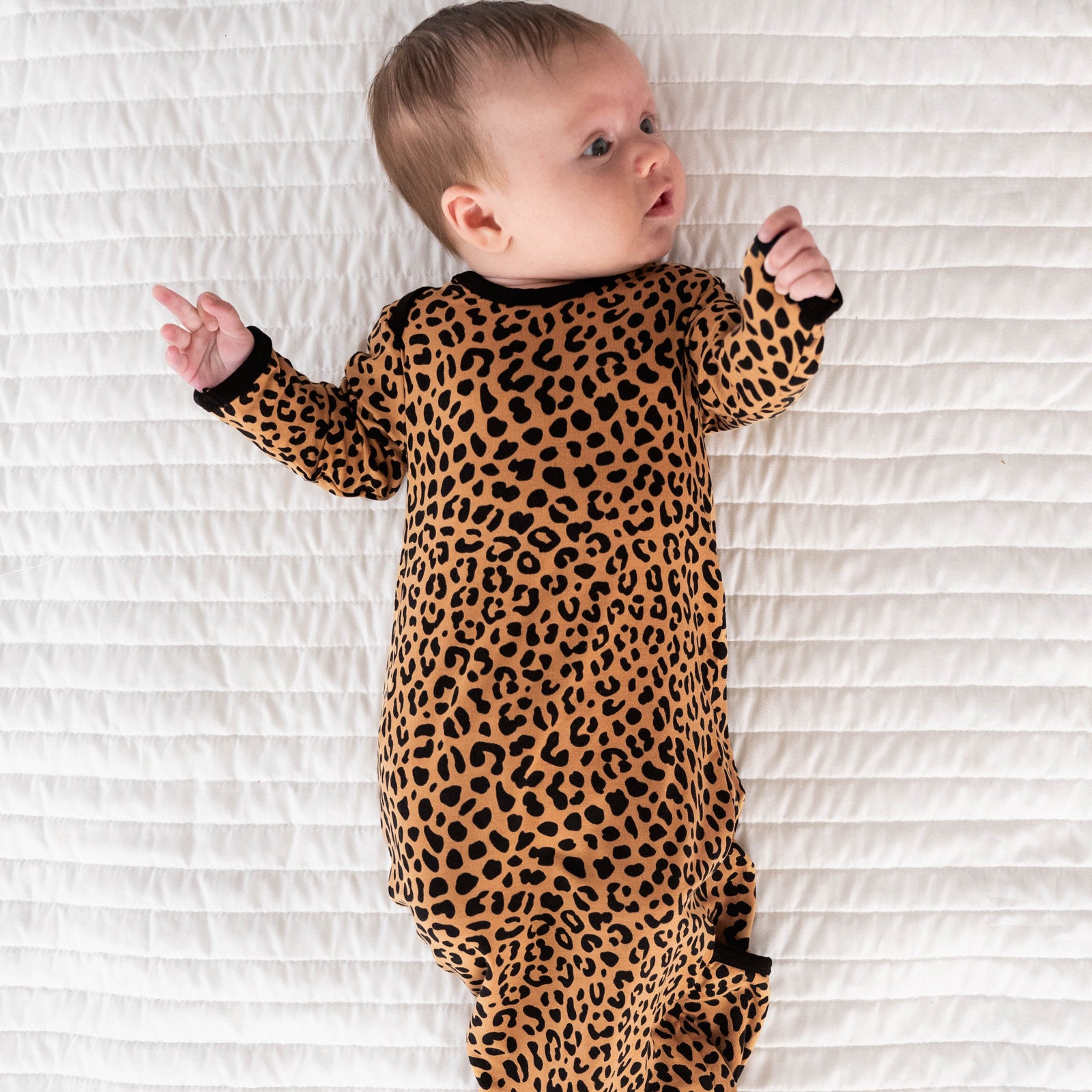 Top view image of baby laying down while in the Classic Leopard Infant Gown