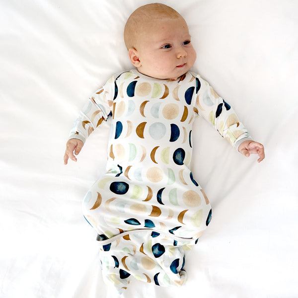 baby laying down wearing the luna neutral gown