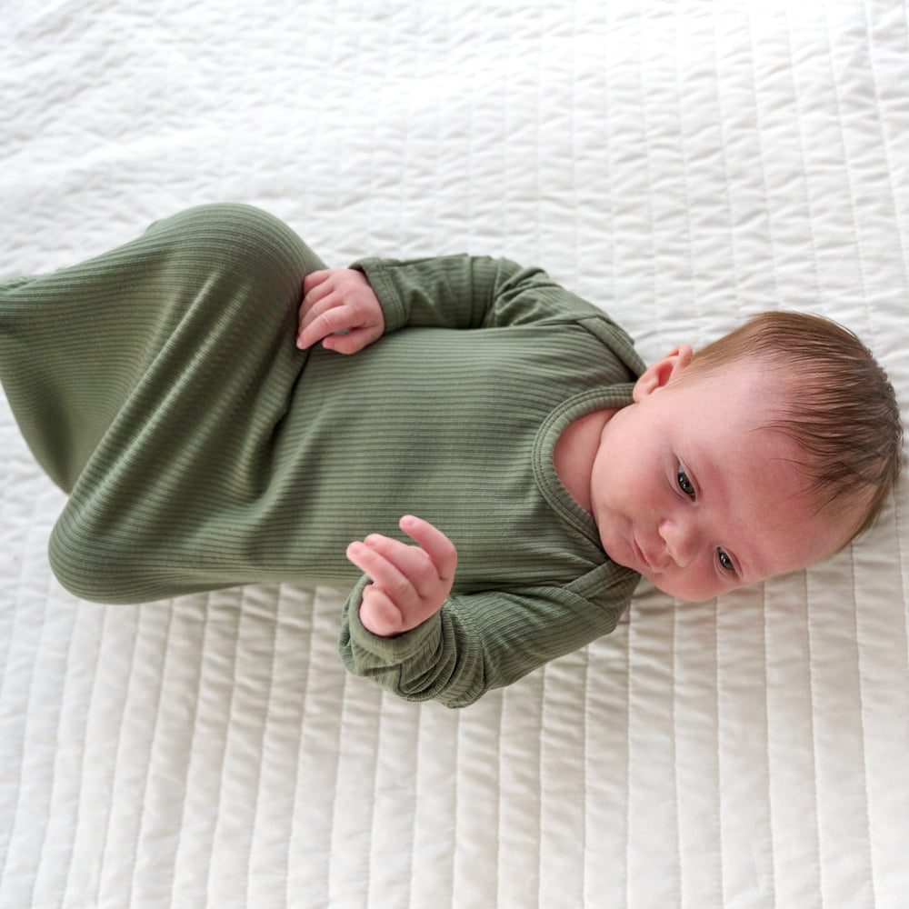 Top view image to the side of baby laying down while wearing the Moss Ribbed Infant Gown