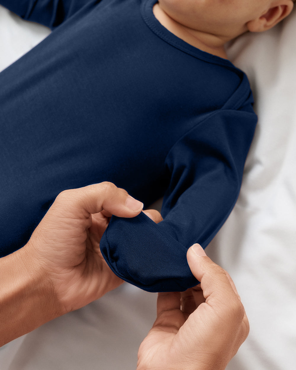 Adult demonstrating the hand fold-over feature on the Classic Navy Infant Gown