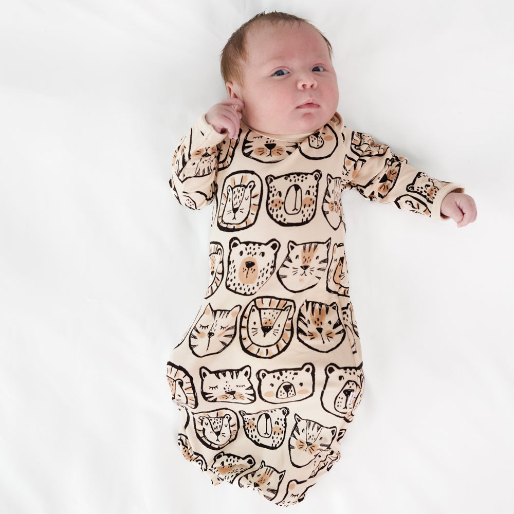 Image of a child laying on a bed wearing a Lions, Tigers, and Bears infant gown