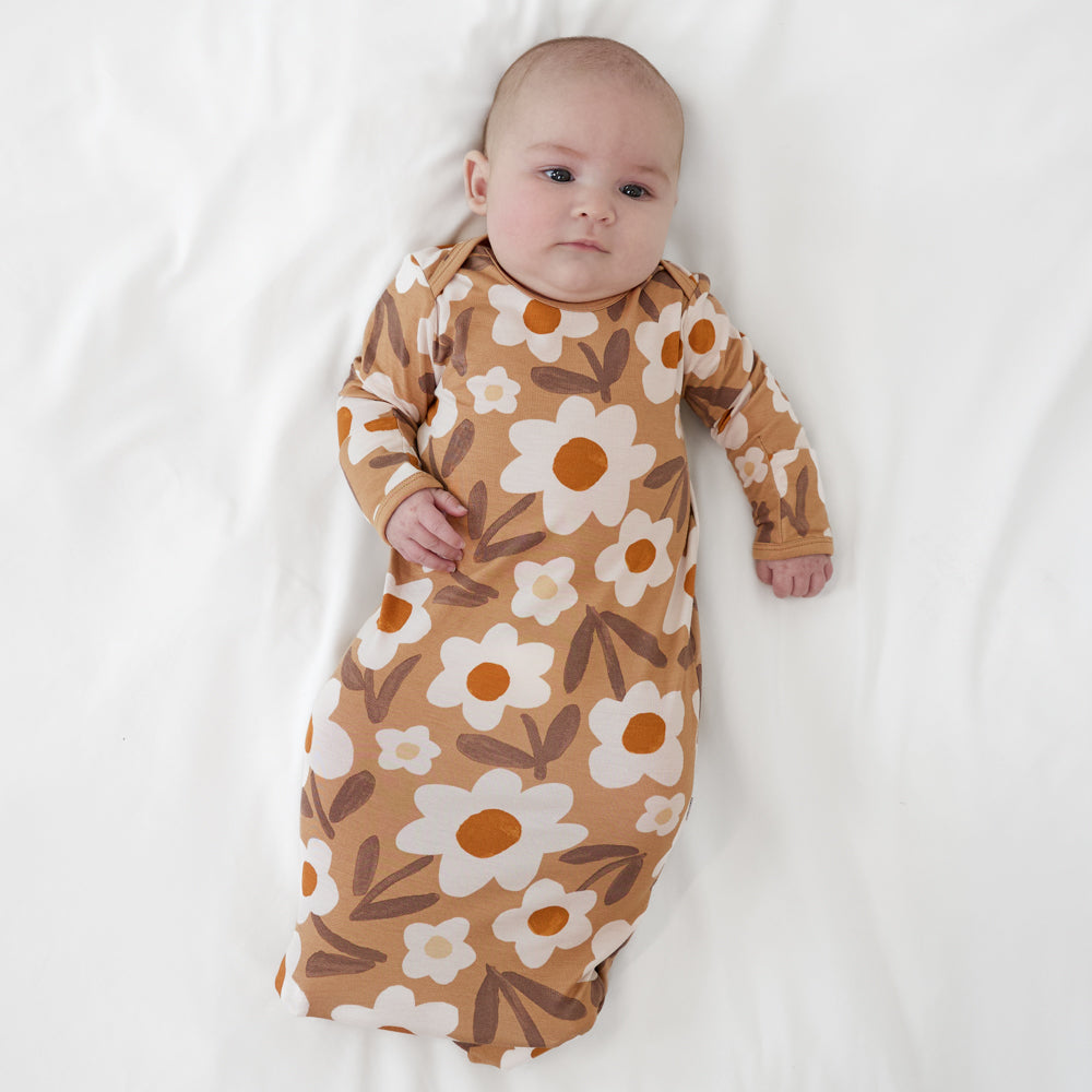 Image of a child laying on a bed wearing a Daisy Daydream infant gown