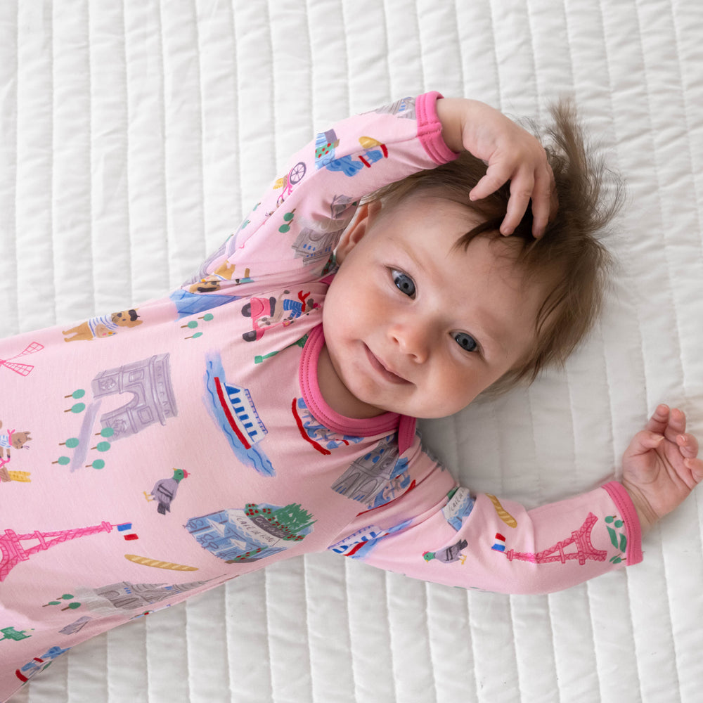 Top view image of baby laying down while in the Pink Weekend in Paris Infant Gown