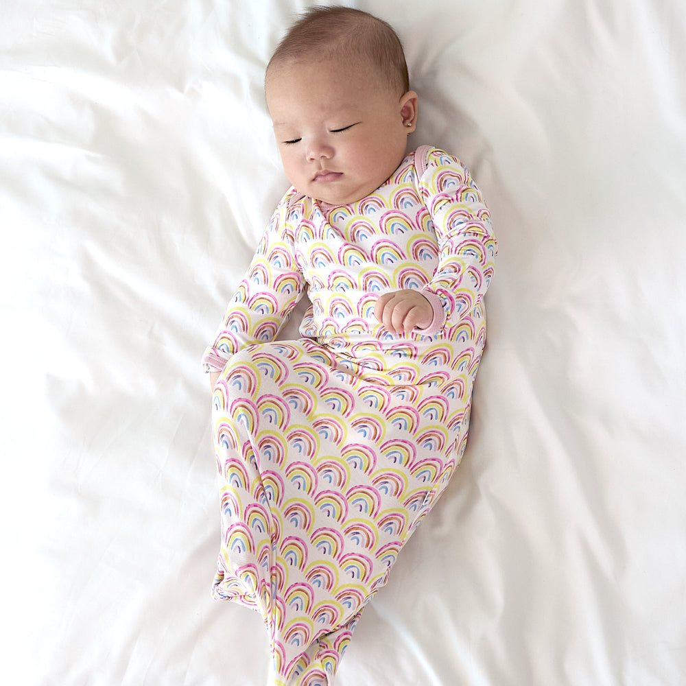 baby in pastel rainbows gown laying down