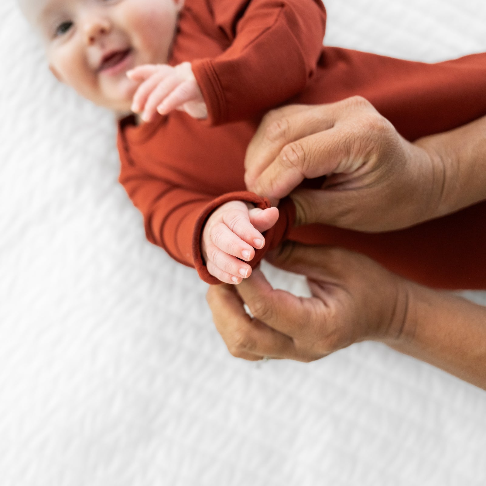 Child wearing a Cozy Rust infant gown. Mom is demonstrating the folded over mitten