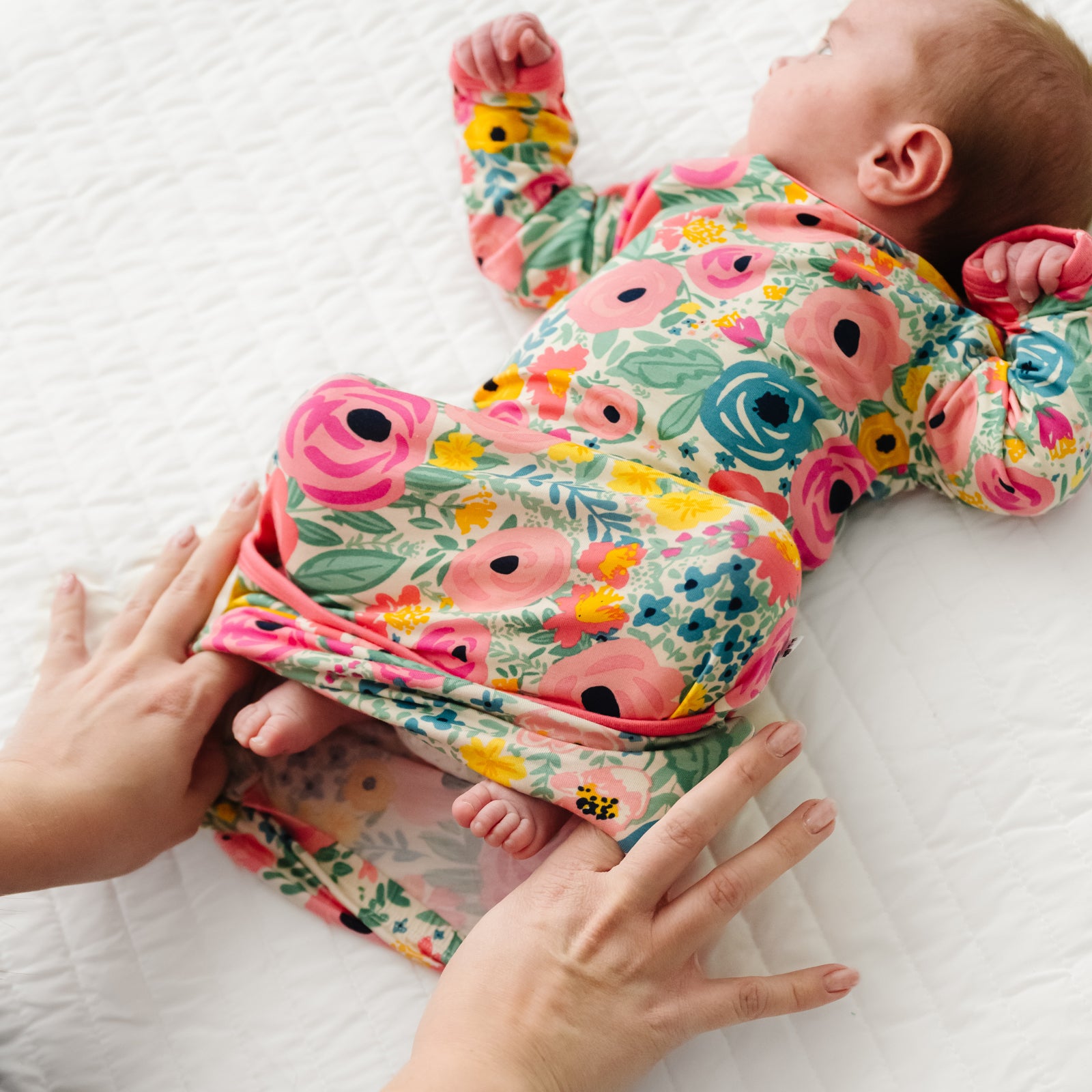 Child laying on a bed wearing a Secret Garden Infant Gown demonstrating the fold over bottom