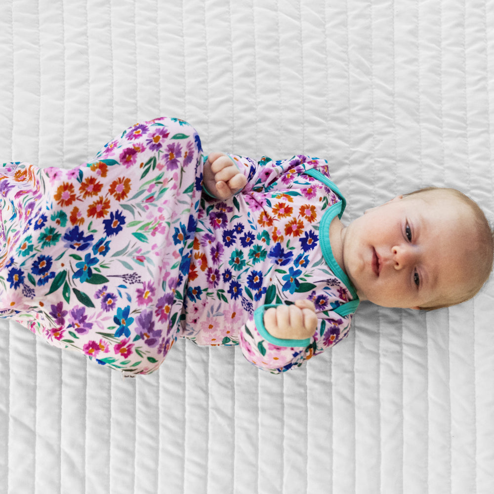 Child laying on a bed wearing a Sweet Pea Floral infant gown