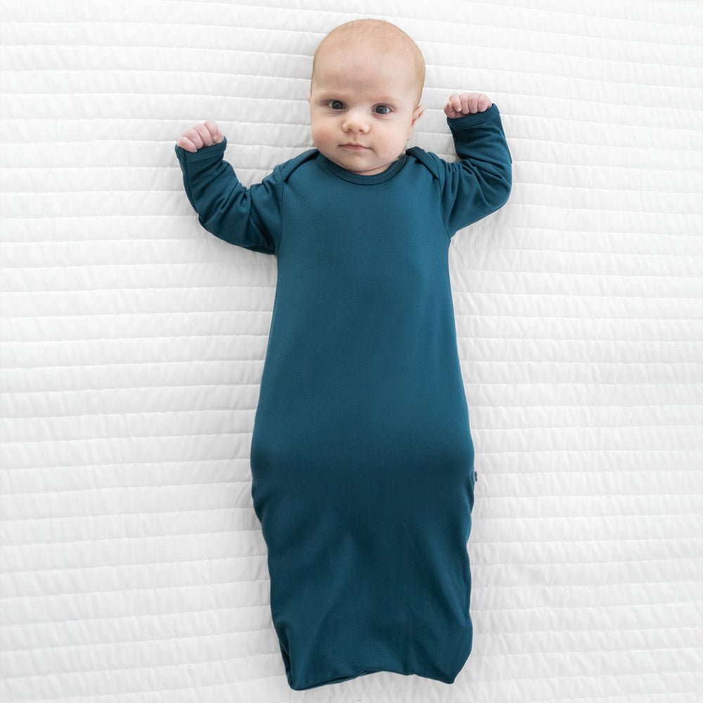 Child laying on a bed wearing a Cozy Twilight Teal infant gown