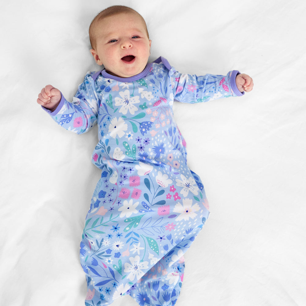 Child laying on a bed wearing a Magical Meadow infant gown