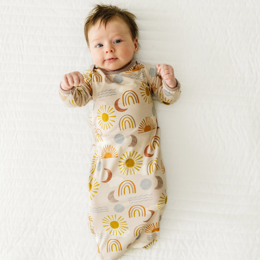 Child laying on a bed wearing a Desert Sunrise infant gown