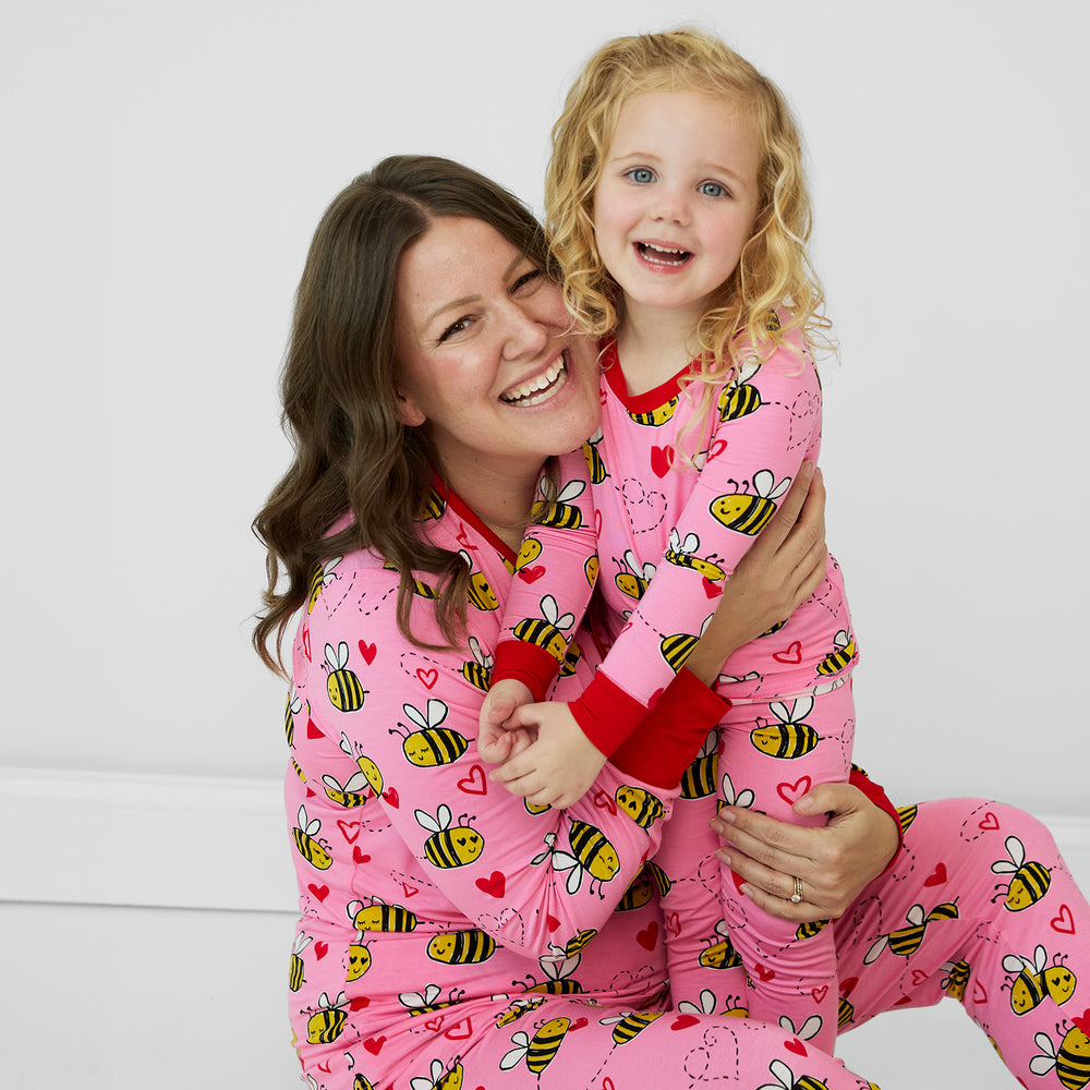 Close up image of mother and daughter embracing wearing Pink Bee Mine pjs in women's and childrens two piece styles