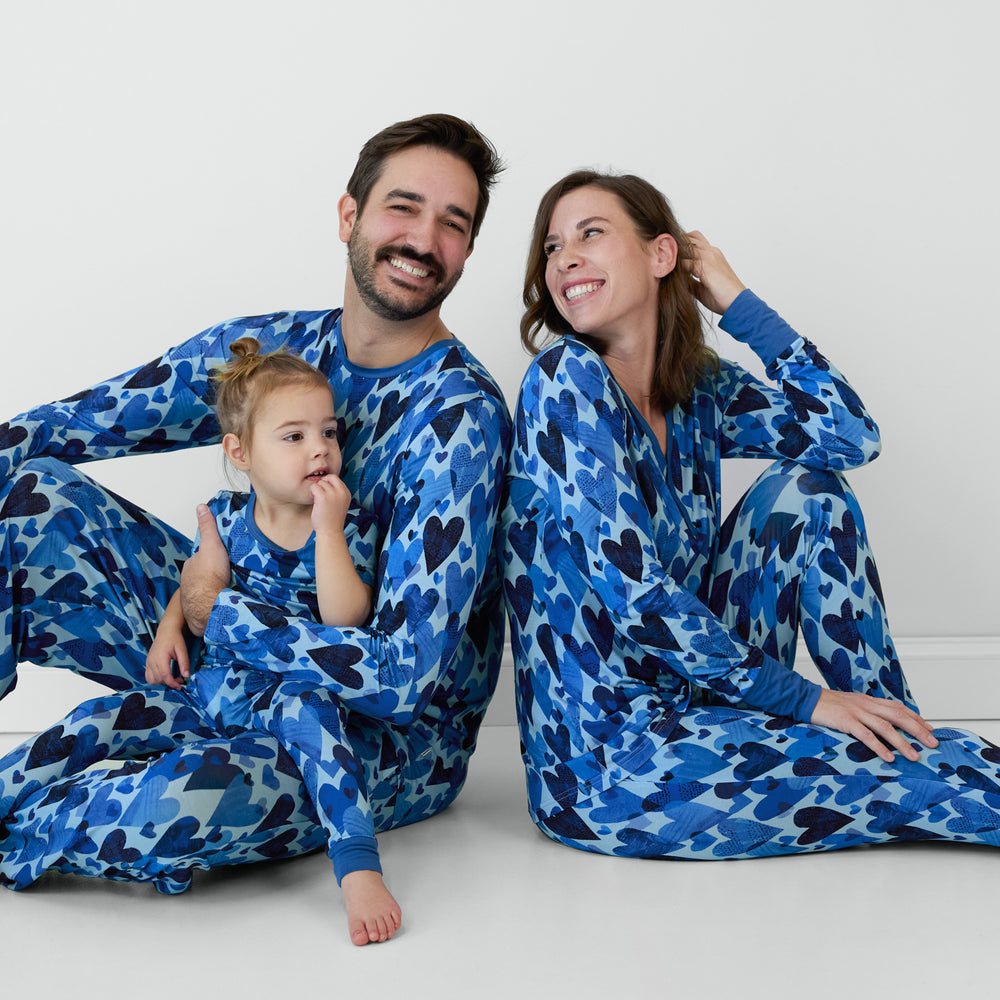 Family sitting in matching in men's, women's and children's Blue Hearts & Crafts pajamas.