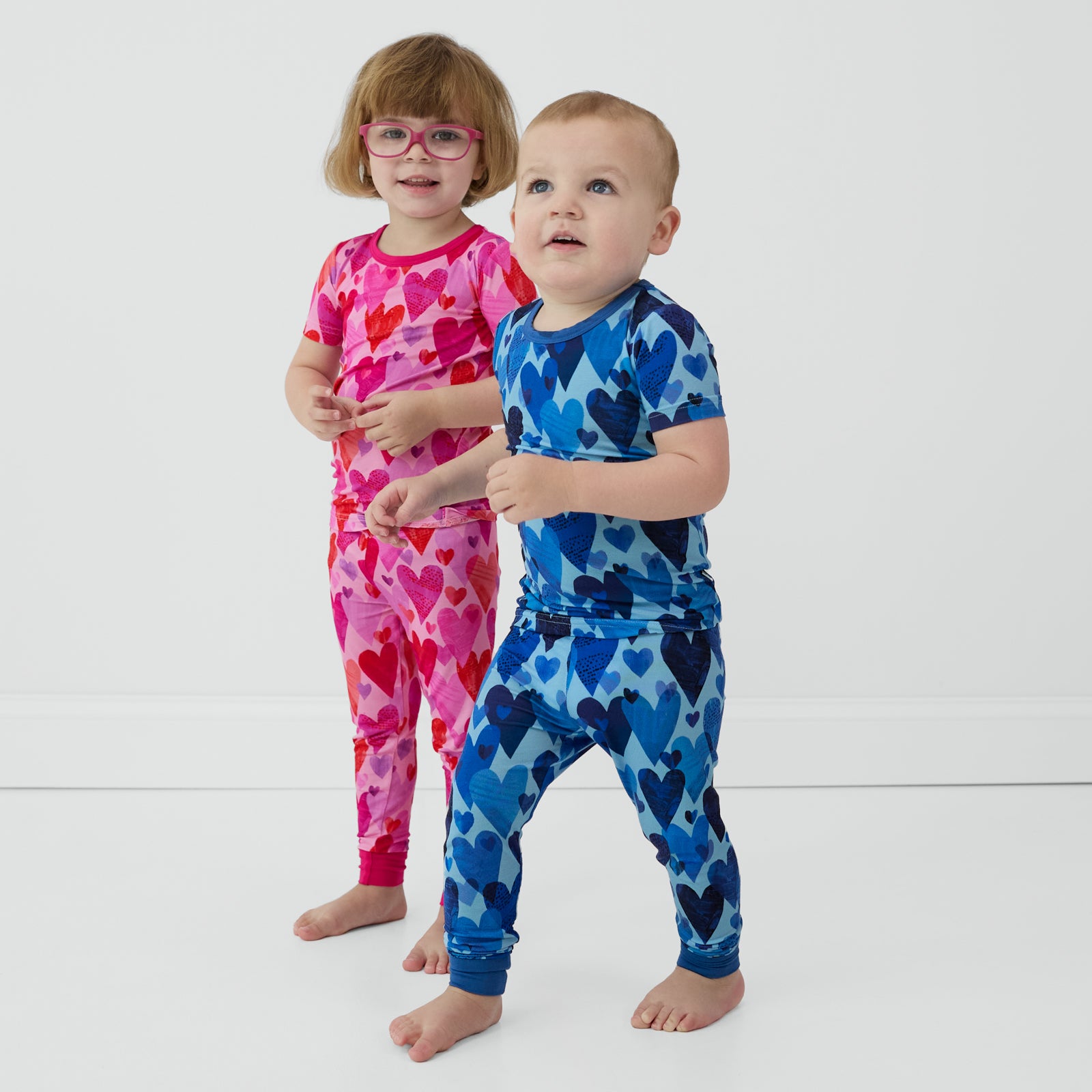 Sibling matching in pink and blue Hearts & Crafts two-piece pajama sets.