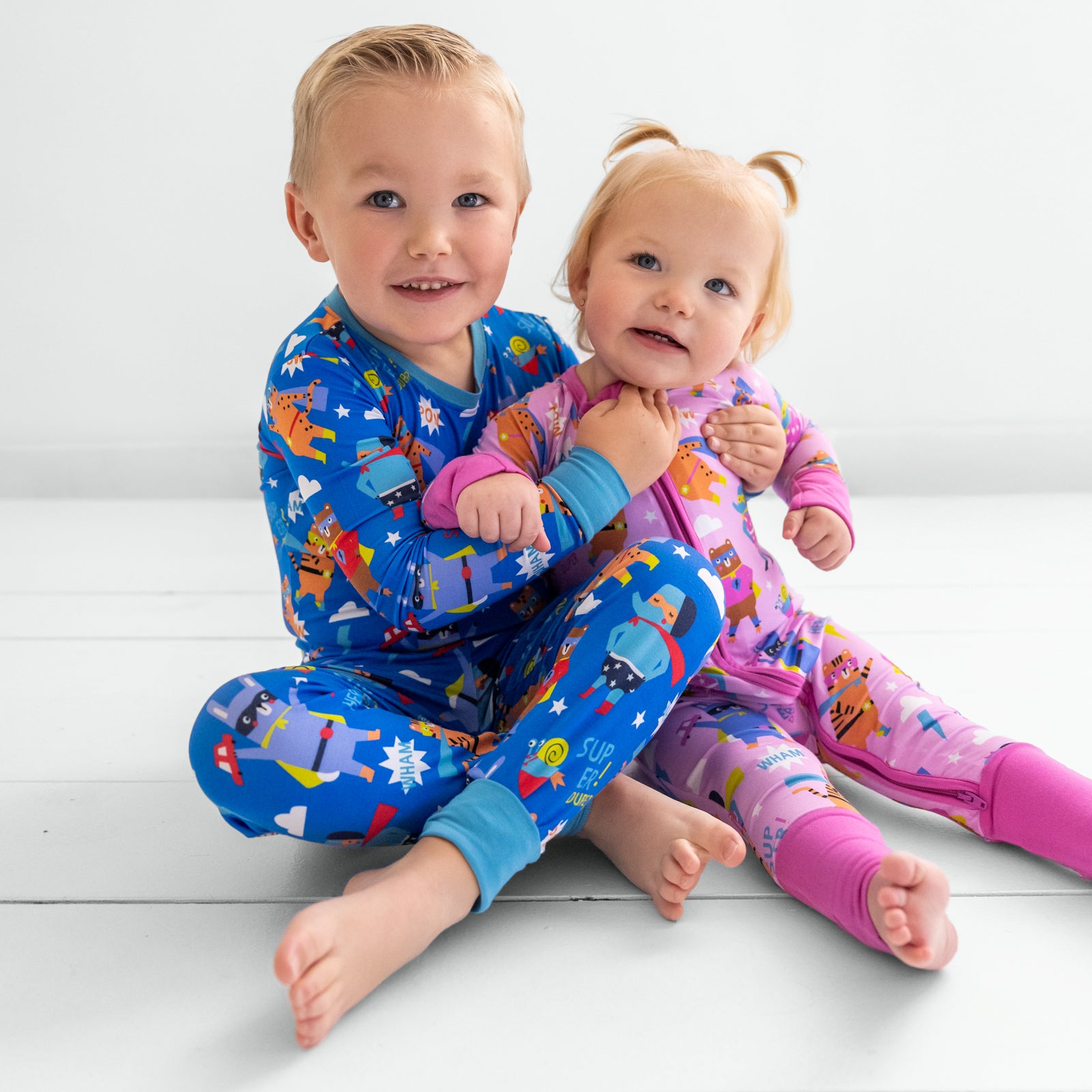 Two children sitting together wearing matching blue and pink Sleepy Heroes styles