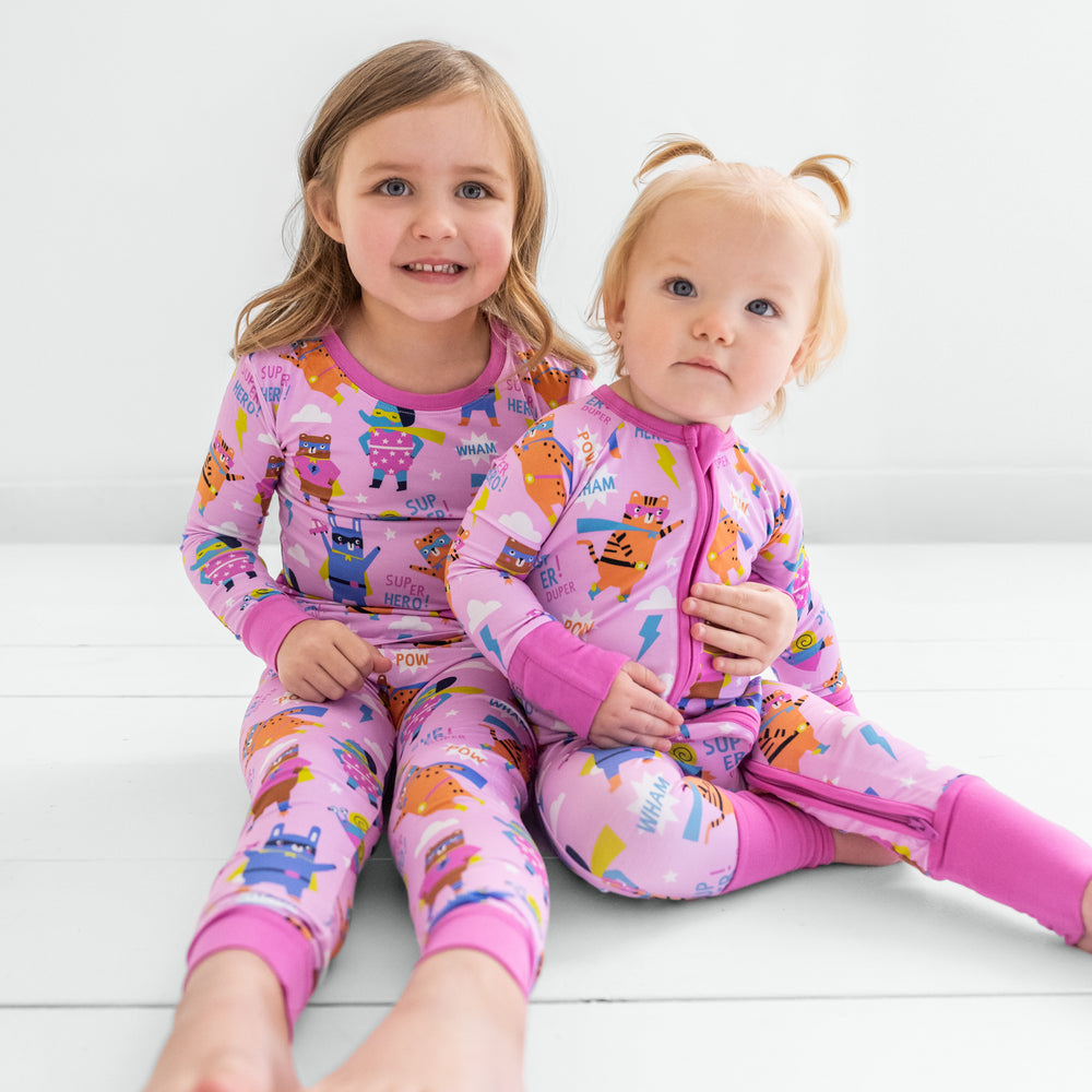 Two children sitting wearing matching pink sleepy heroes bamboo pajama styles