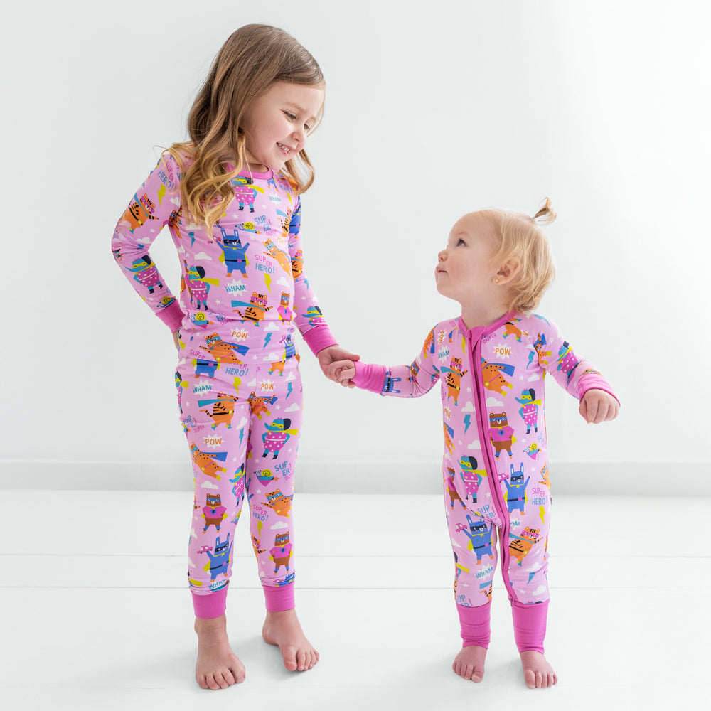 Two children standing holding hands wearing matching pink sleepy heroes styles