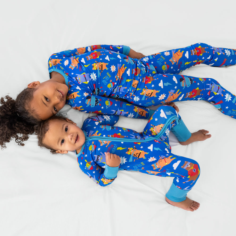 Two children laying together wearing matching Blue Sleepy Heroes styles