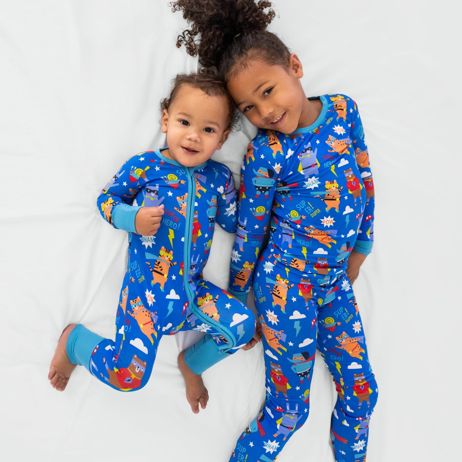 Two children laying wearing the matching Blue Sleepy Heroes styles