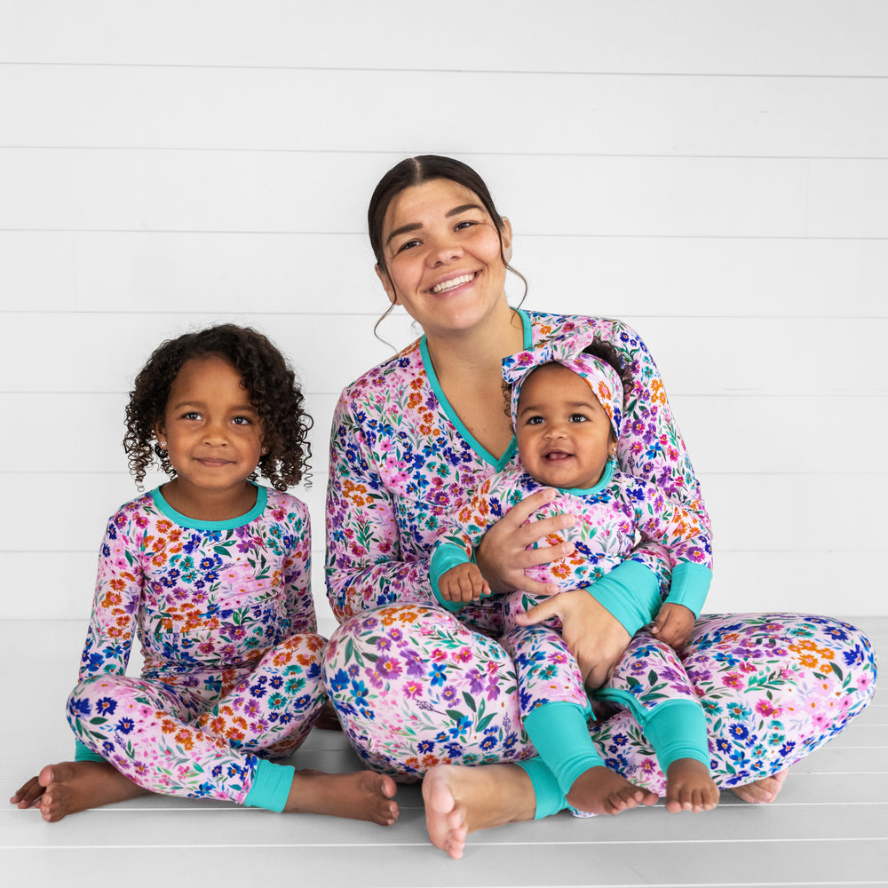 Mother and her two children sitting together wearing Sweet Pea Floral pjs. Mom is wearing women's Sweet Pea Floral pjs in women's top and bottom and children are wearing matching two piece and crescent zippy styles